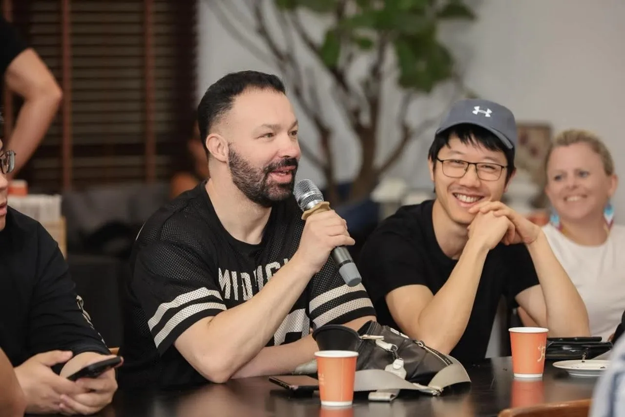Jake Lam (cap and glasses) sitting in on a session at SEO Mastery Summit 2026, listening to a speaker mid-talk